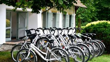 A row of white bicycles parked outside a building with a door and windows.