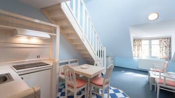 Una cocina compacta con zona de comedor, una escalera y una ventana con cortinas.