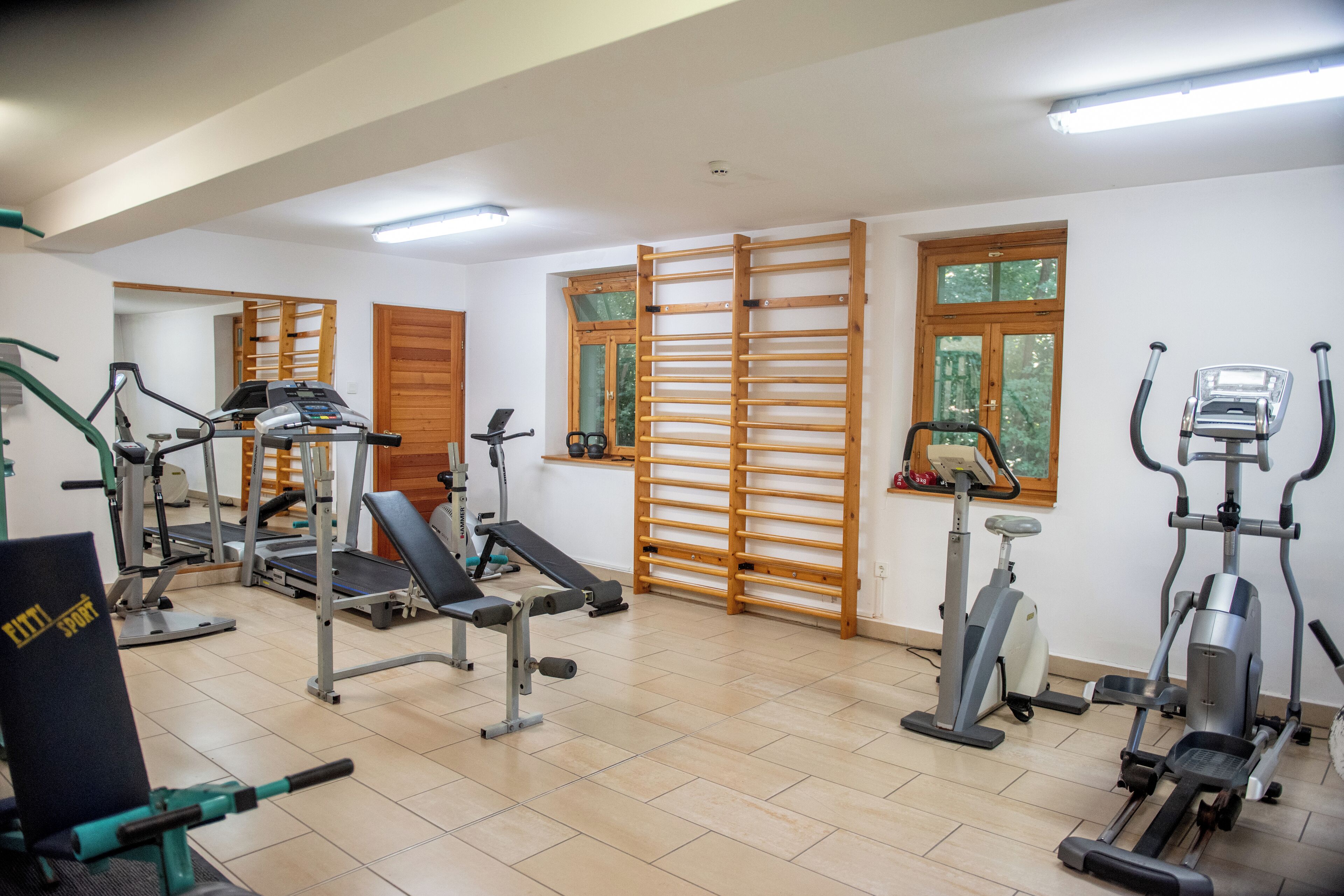 A gym with various exercise equipment, including treadmills, stationary bikes, and weight machines.