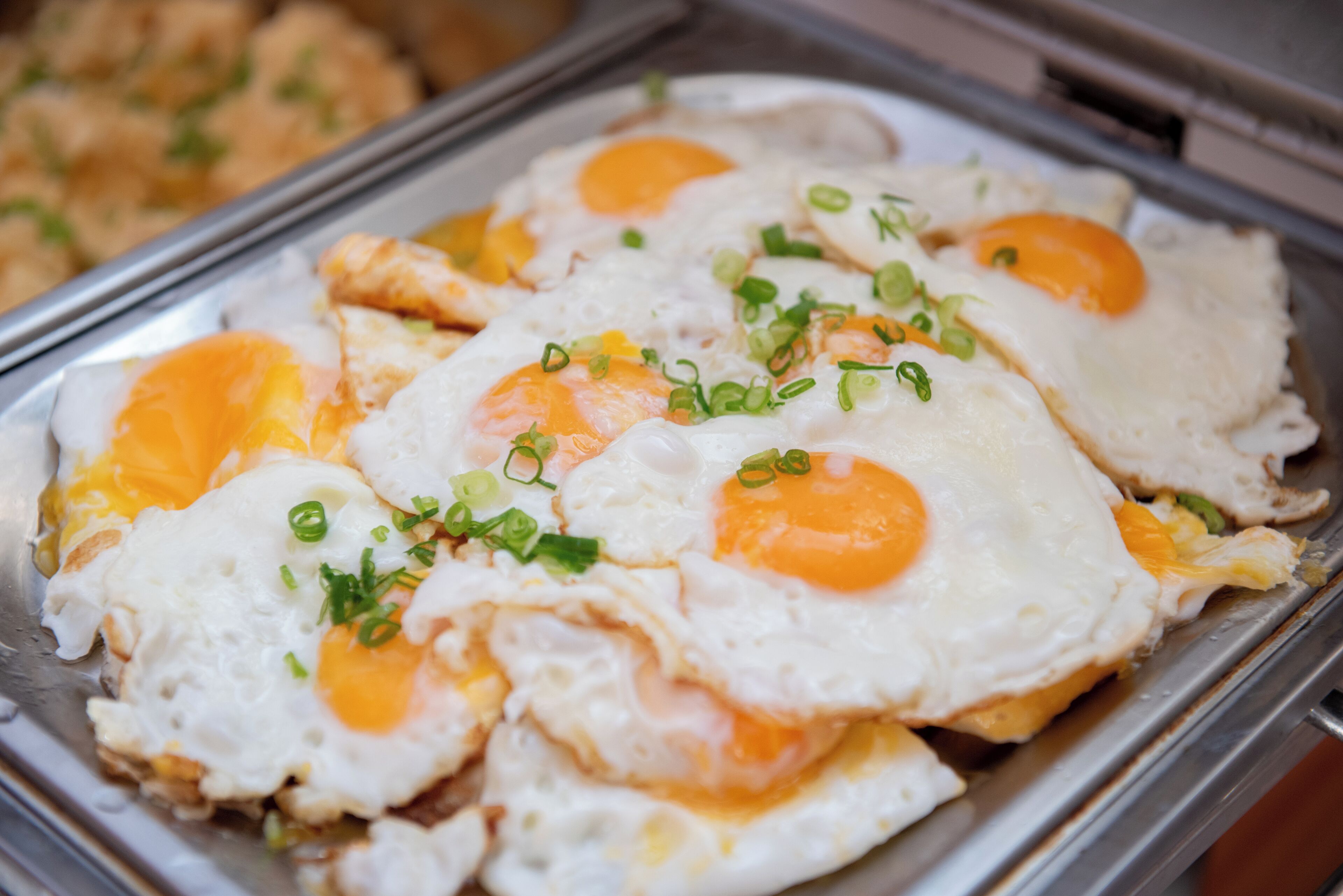 Una bandeja con huevos estrellados, adornados con cebollines picados.