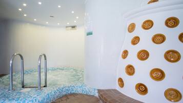 A spa area with a hot tub, a tiled wall, and a large white column with circular patterns.