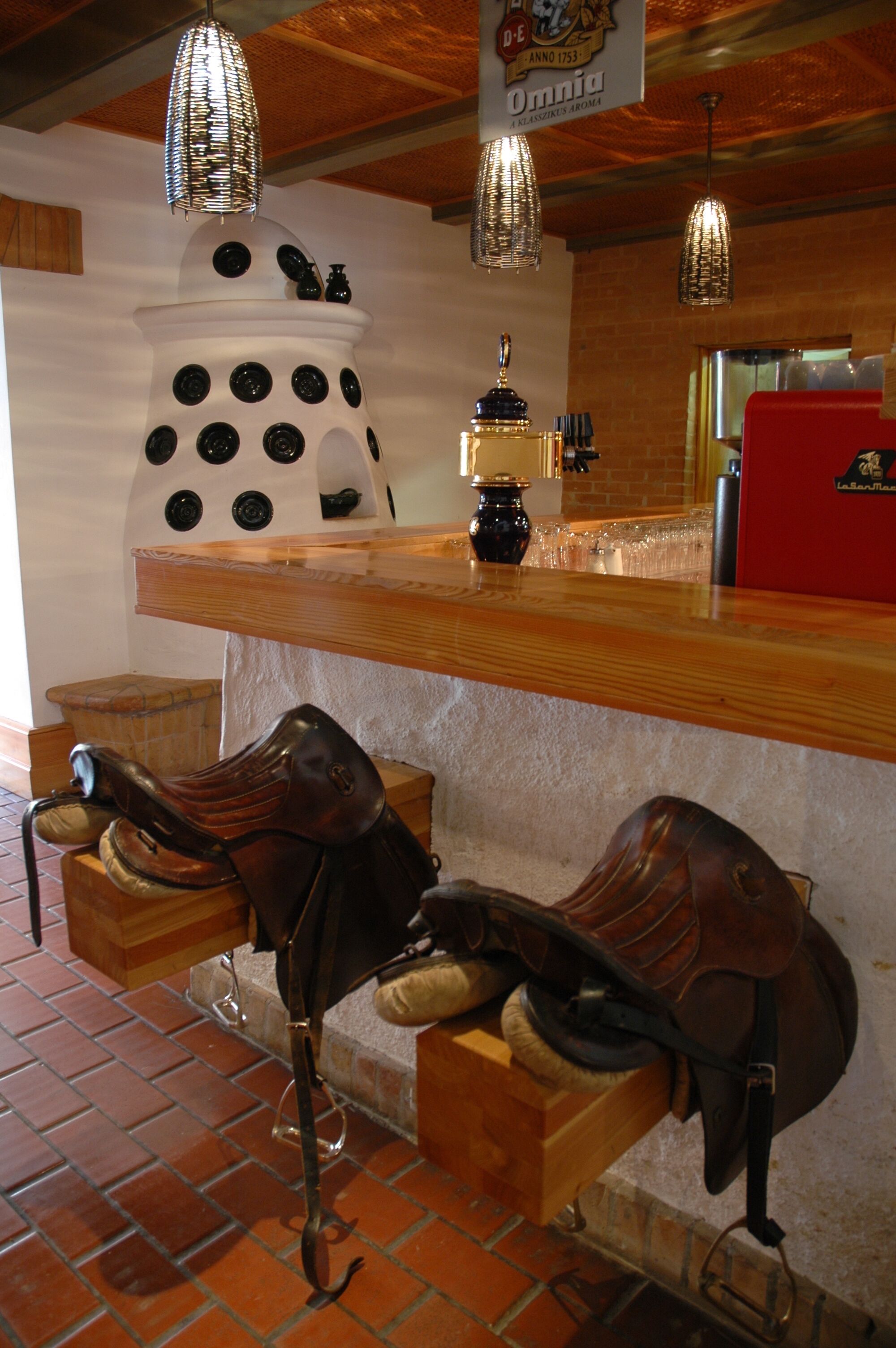 Zona de bar con mostrador de madera, luces colgantes y un adorno en la pared.