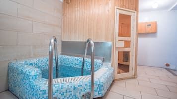 Relax in a serene spa room with a rectangular hot tub and mosaic tile design, complemented by a wooden panel wall and a convenient storage cabinet.