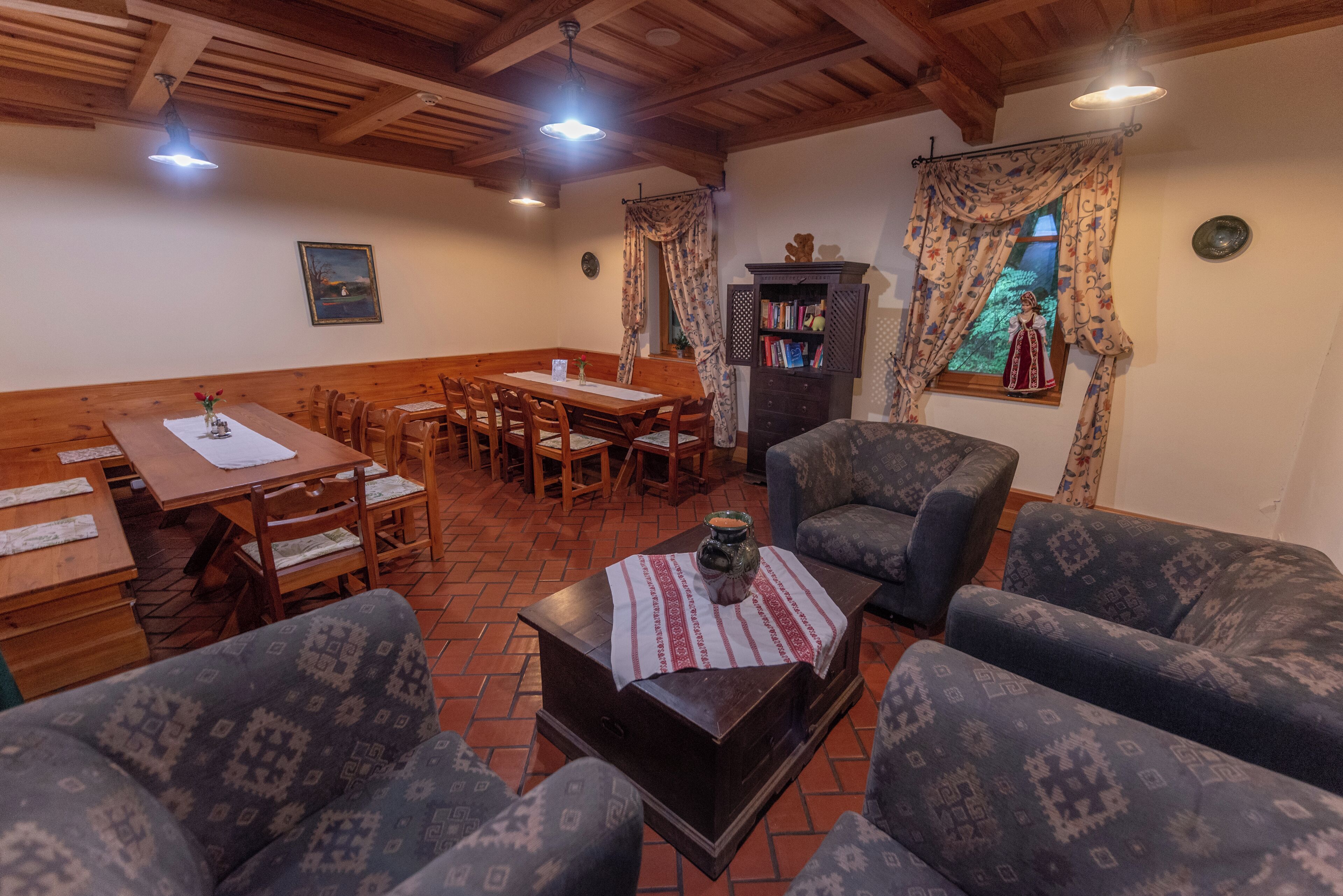 A cozy living area with a wooden dining table, blue patterned sofas, and a coffee table with a decorative item.