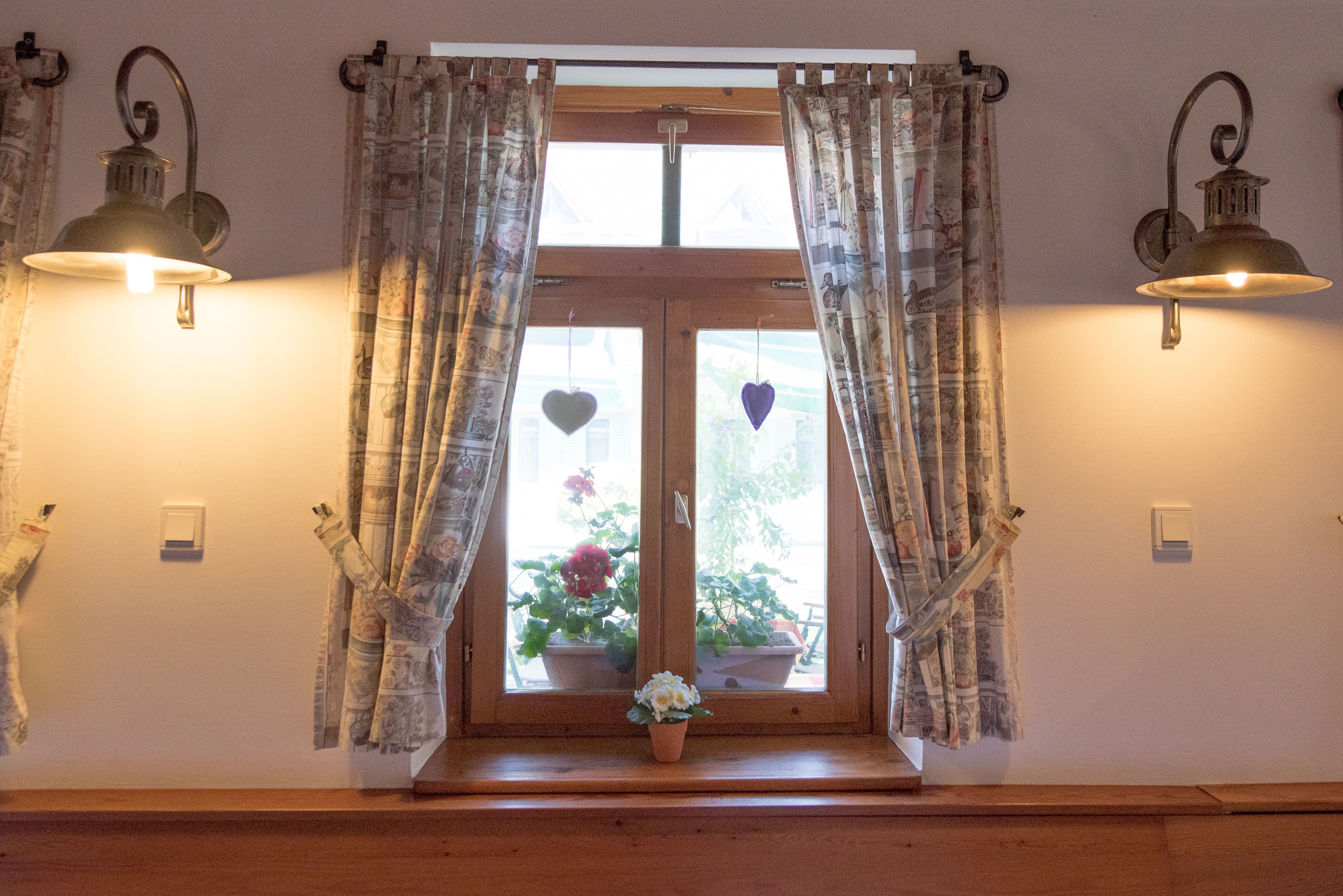 A room with a window, curtains, and wall-mounted lights.