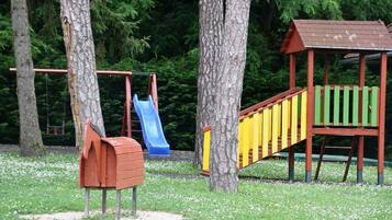 Une aire de jeux avec un toboggan, une balançoire et une petite structure en bois.