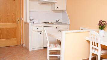 A compact kitchen with a microwave, coffee maker, and a small dining table with chairs.