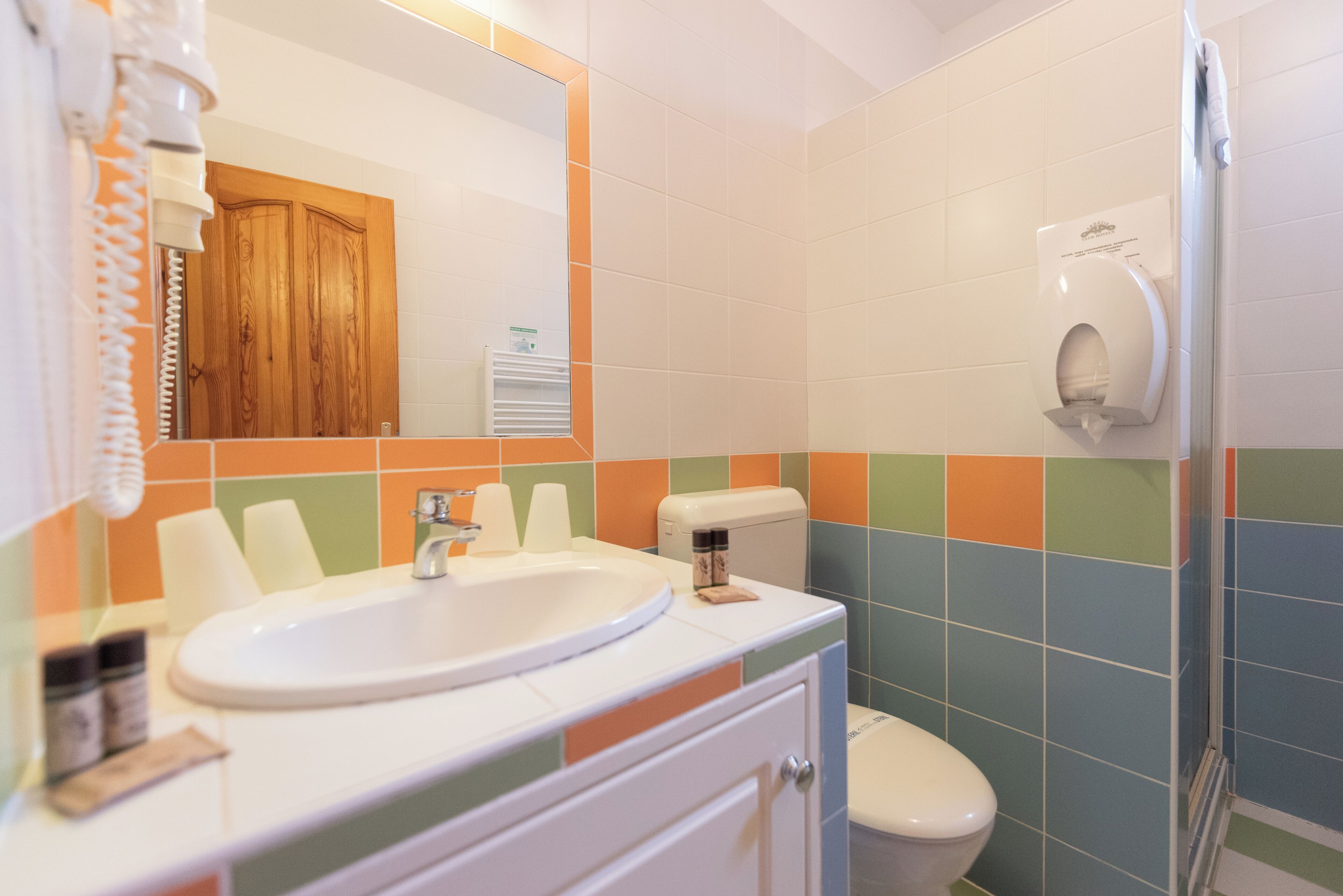 A bathroom with a sink, toilet, and hand dryer.