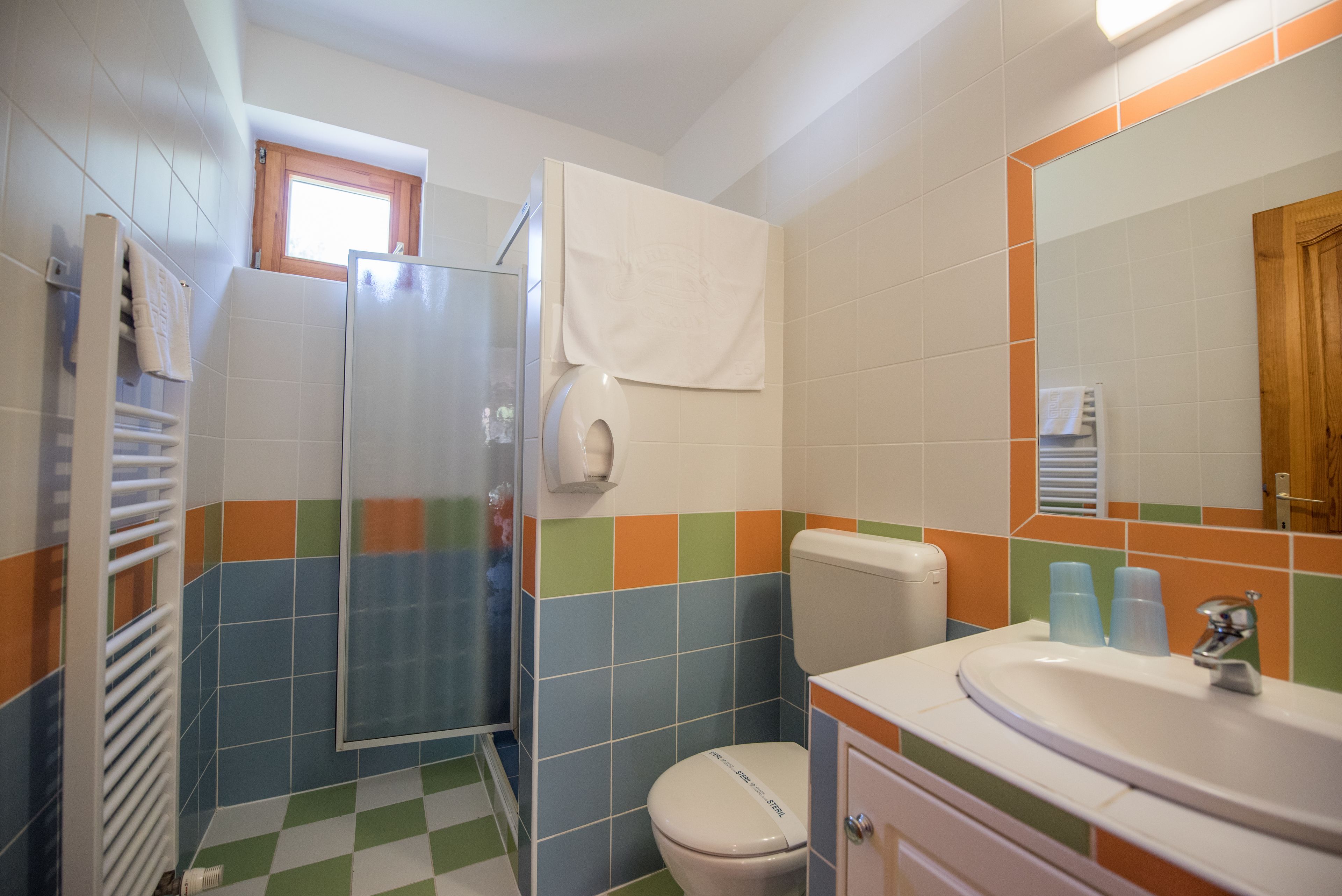 A bathroom with a shower, toilet, sink, and a mirror.