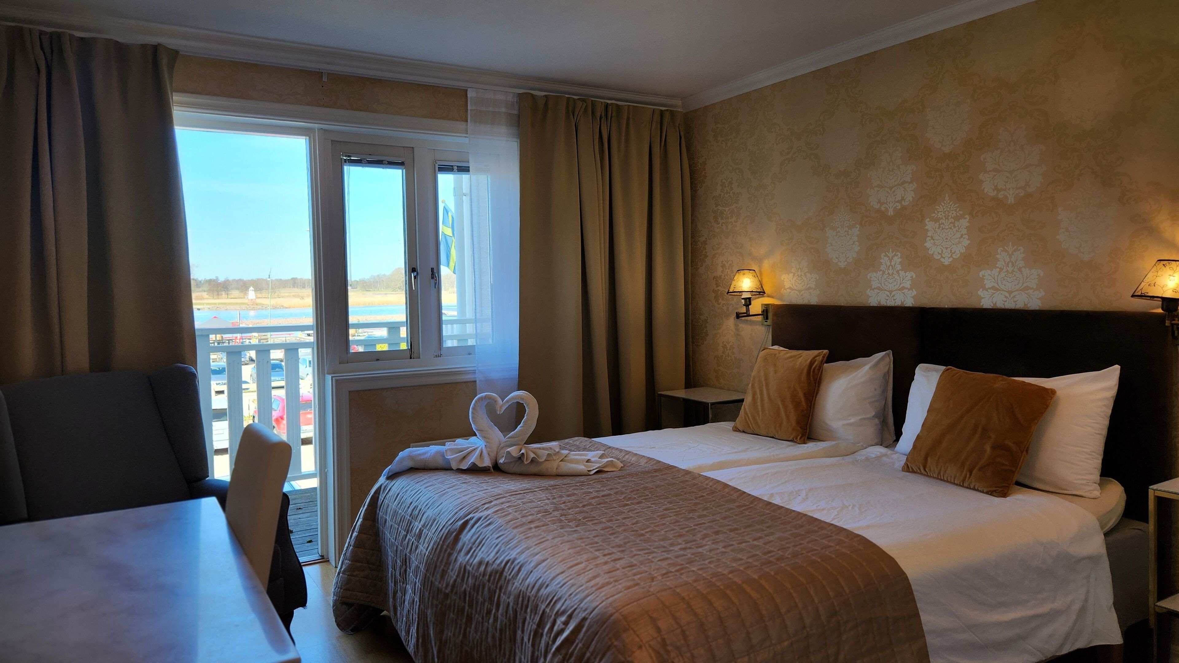 A hotel room with a bed, a desk, and a view of the outdoors.