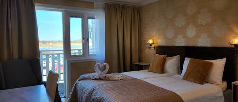 A hotel room with a bed, a desk, and a view of the outdoors.