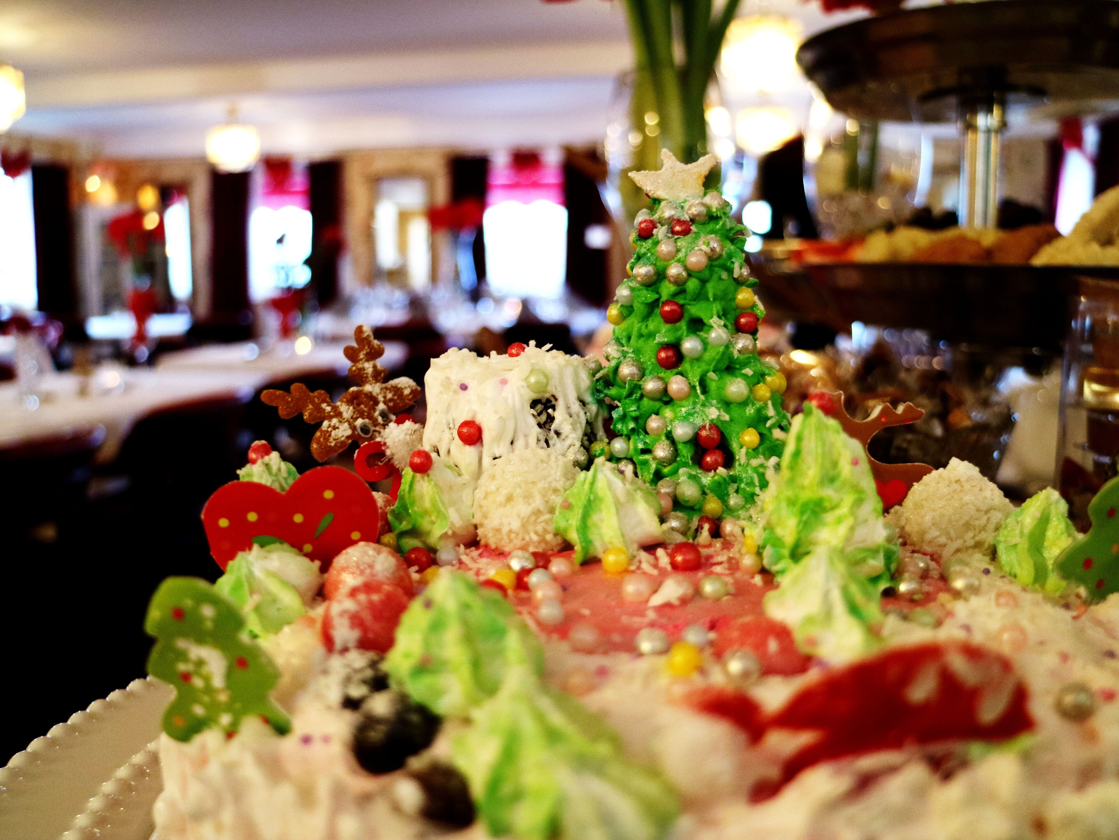 Una exhibición festiva de postres con un árbol de Navidad como centro, rodeada de diferentes ingredientes y adornos.