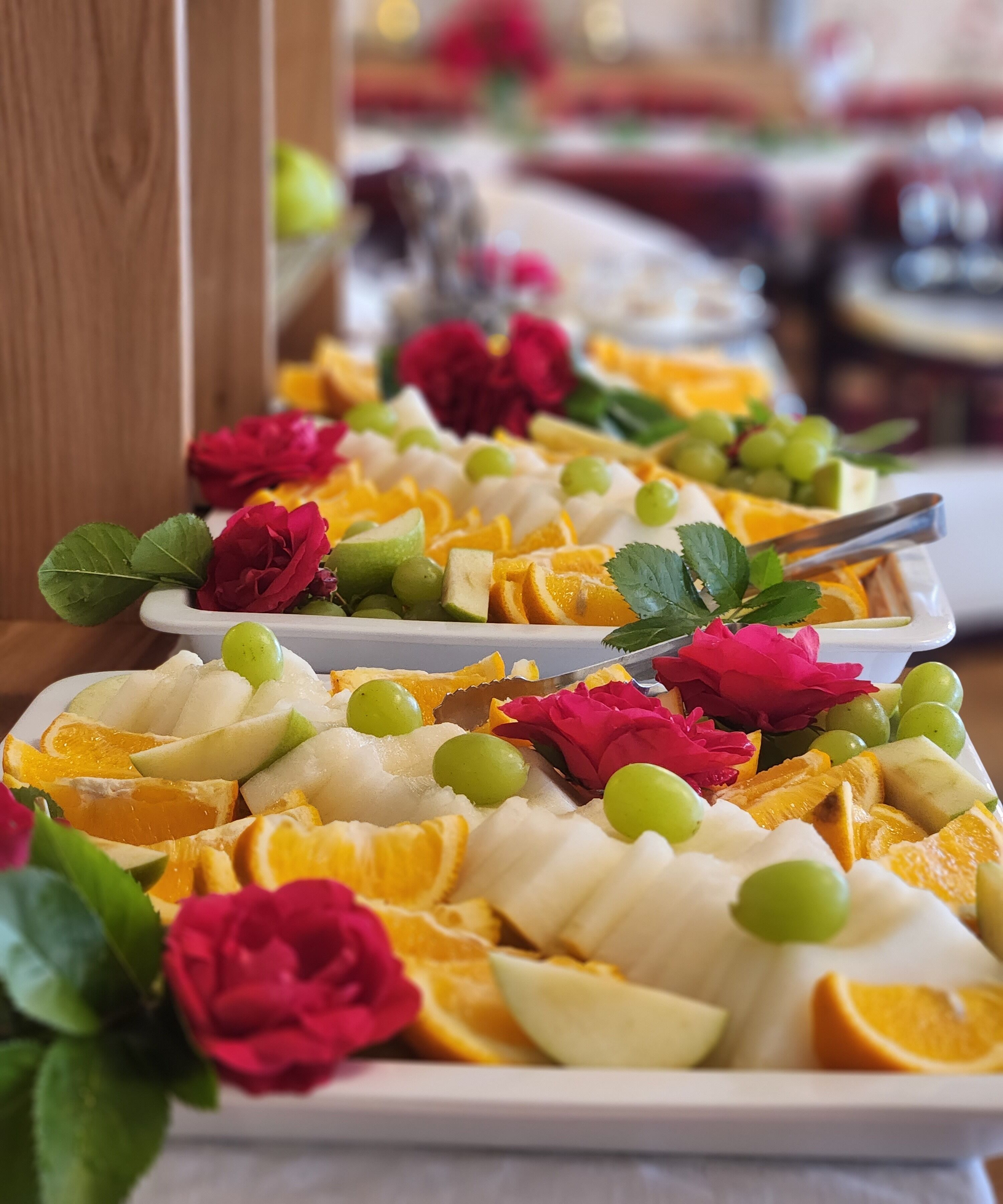 A buffet table with various fruits and flowers.