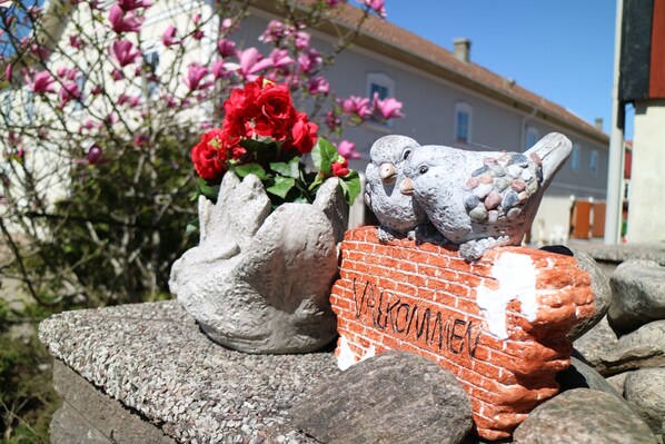 A garden with a brick wall, a bird sculpture, and red flowers.
