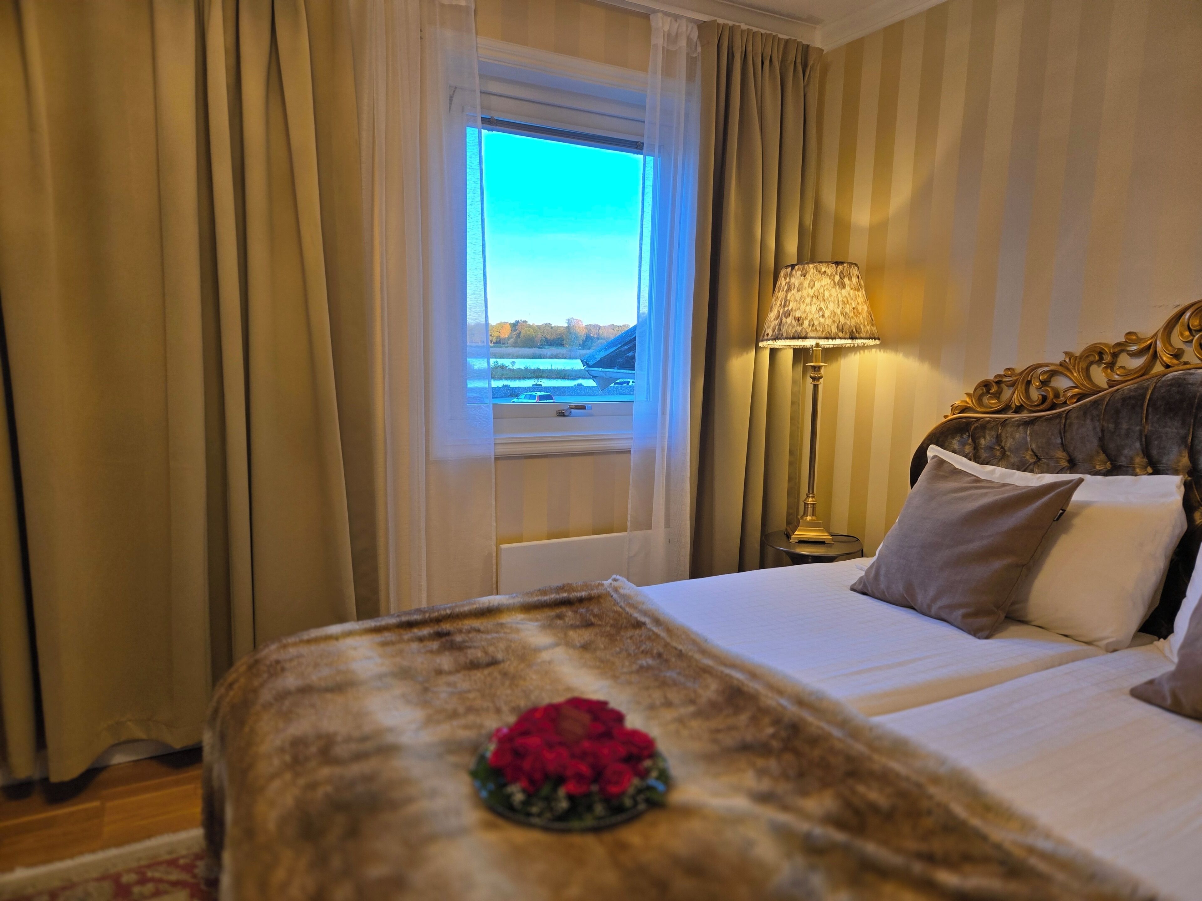 A hotel room with a bed, a lamp, and a window with curtains.