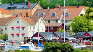 A coastal town with a prominent tower, waterfront buildings, and boats docked near the shore. - Vänerport Lakefront (Mariestad)
