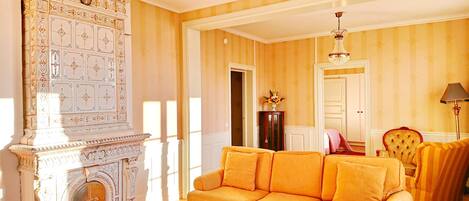 Una habitación con chimenea, sofá, sillón y candelabro.