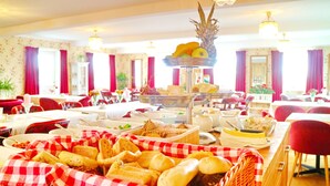 A dining area with multiple tables, red and white checkered tablecloths, and a variety of food items displayed on stands. - Vänerport Lakefront (Mariestad)