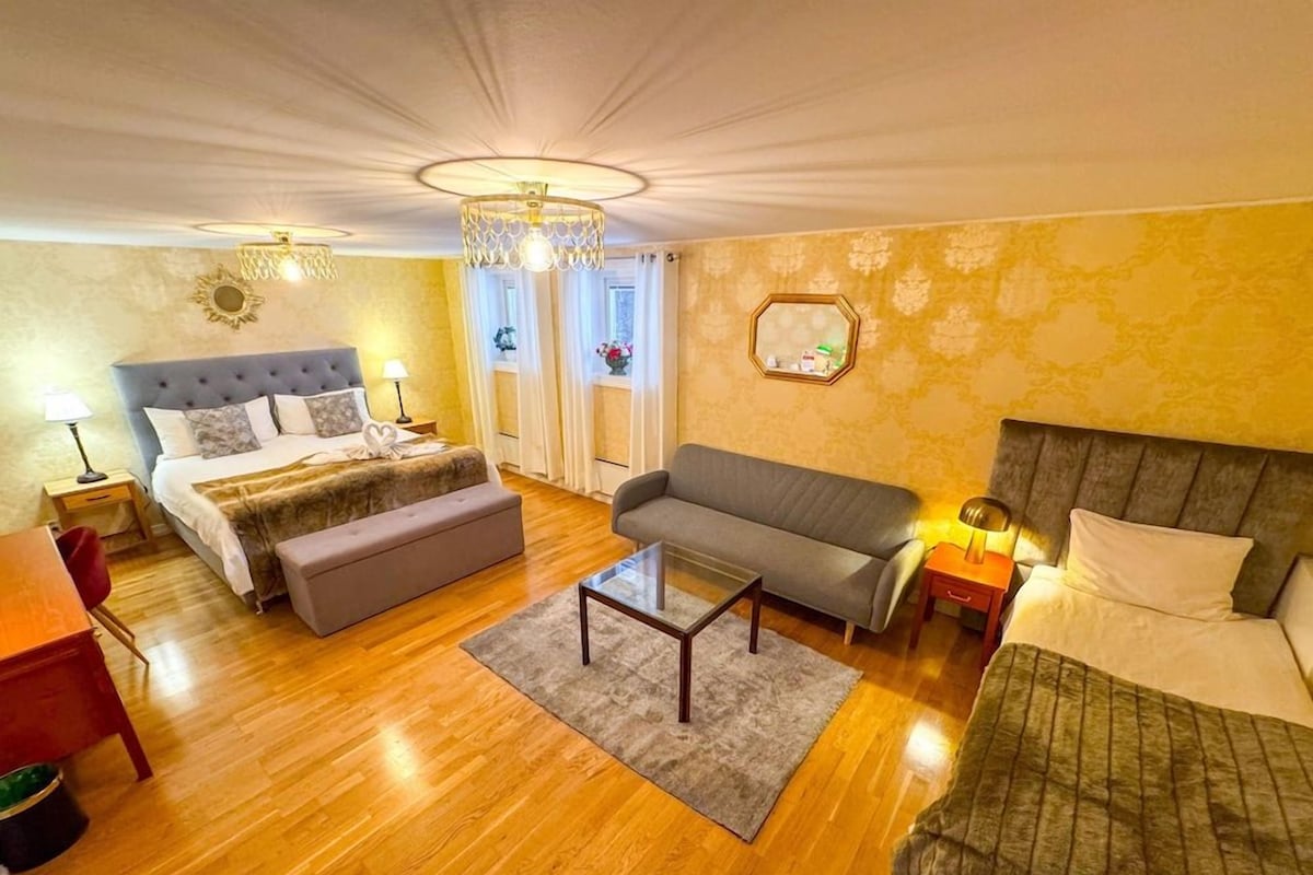 Una habitación de hotel con cama, sofá, una mesita y ventana con cortinas.