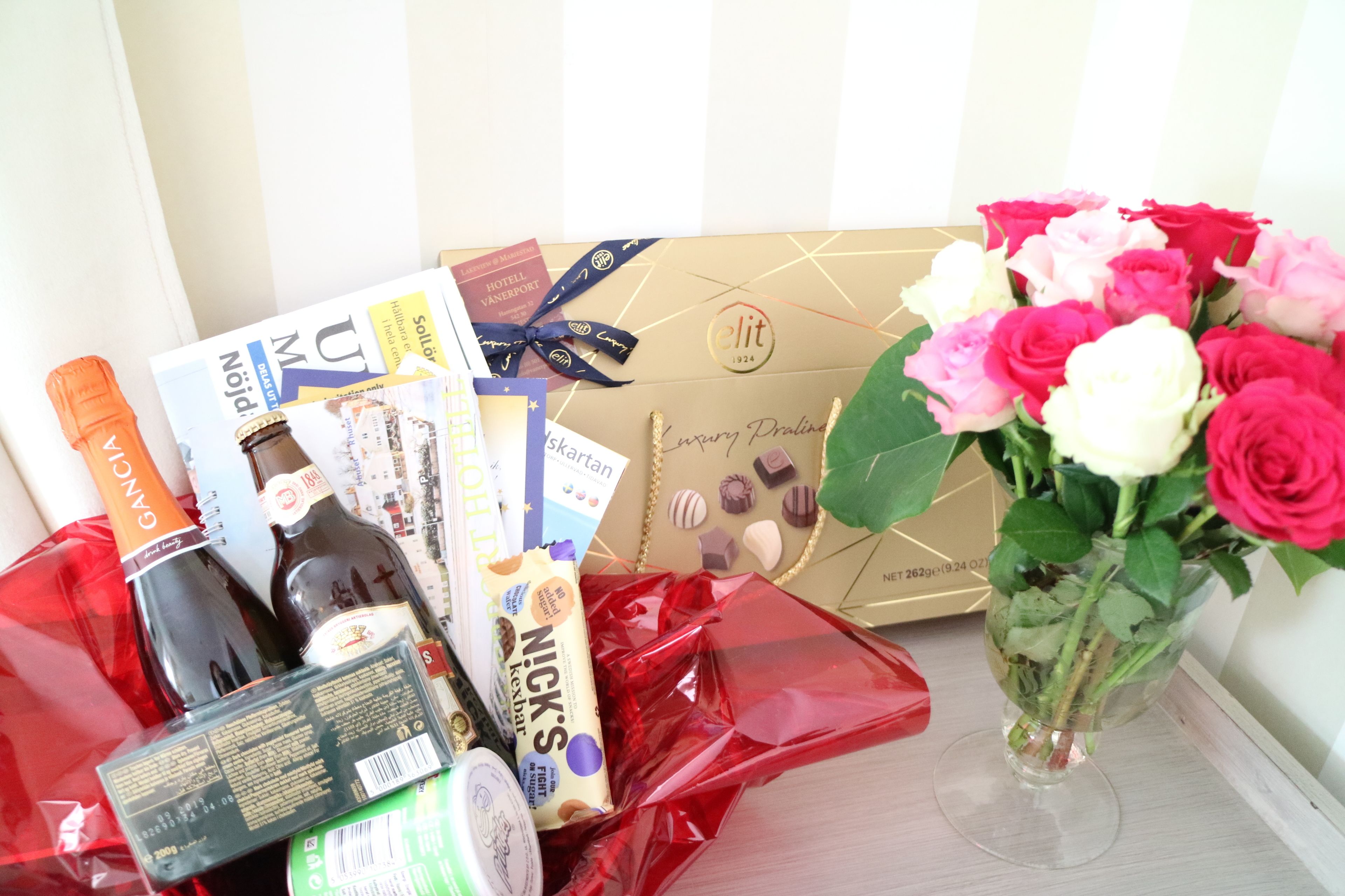 A gift basket with chocolates, a bottle of wine, and a bouquet of roses.