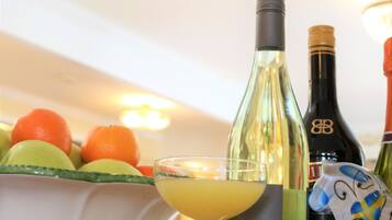 A bar setting with a glass of white wine, a bottle of wine, and a bowl of fruit.