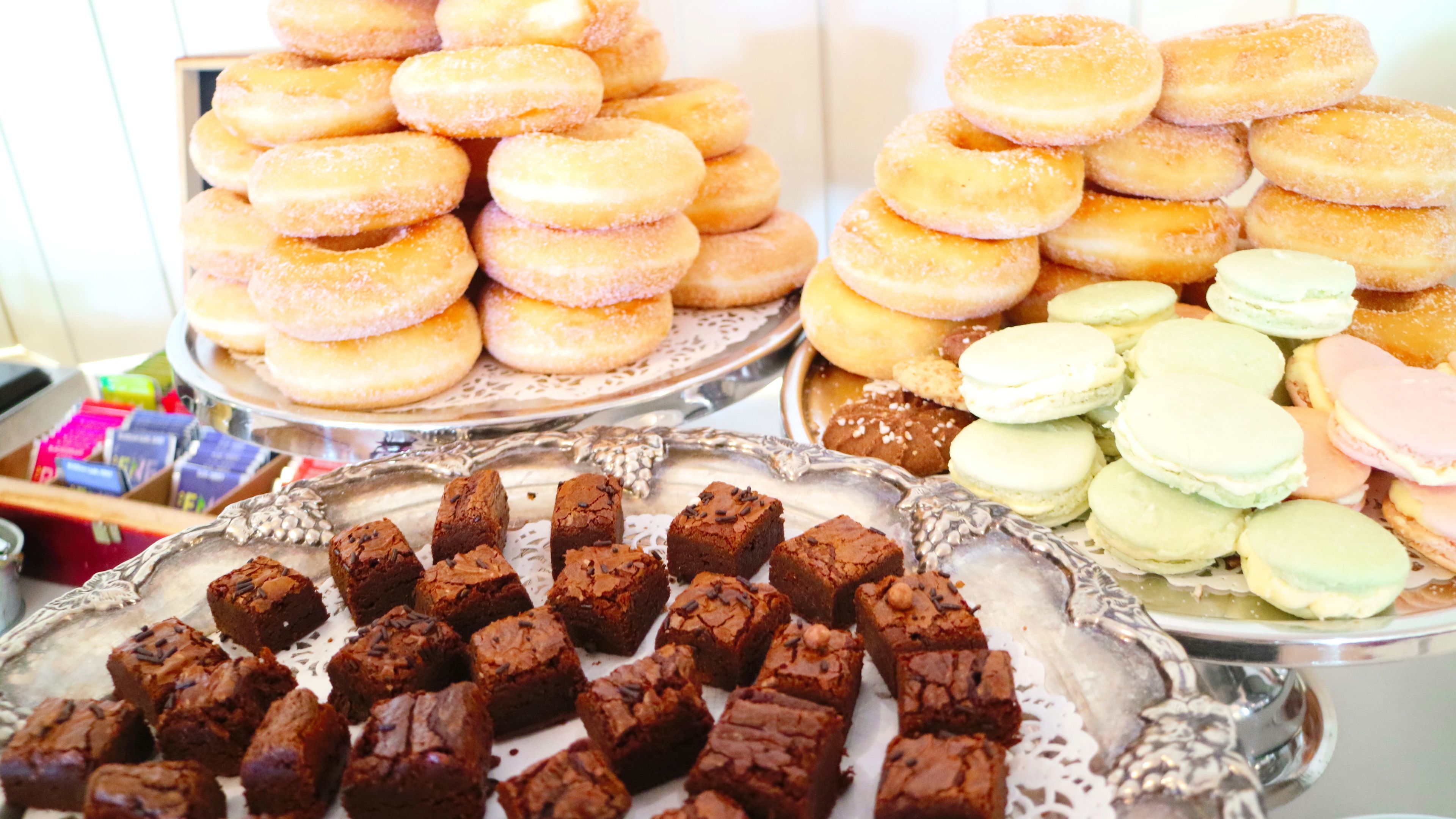 A display of various baked goods including donuts, macarons, and brownies.