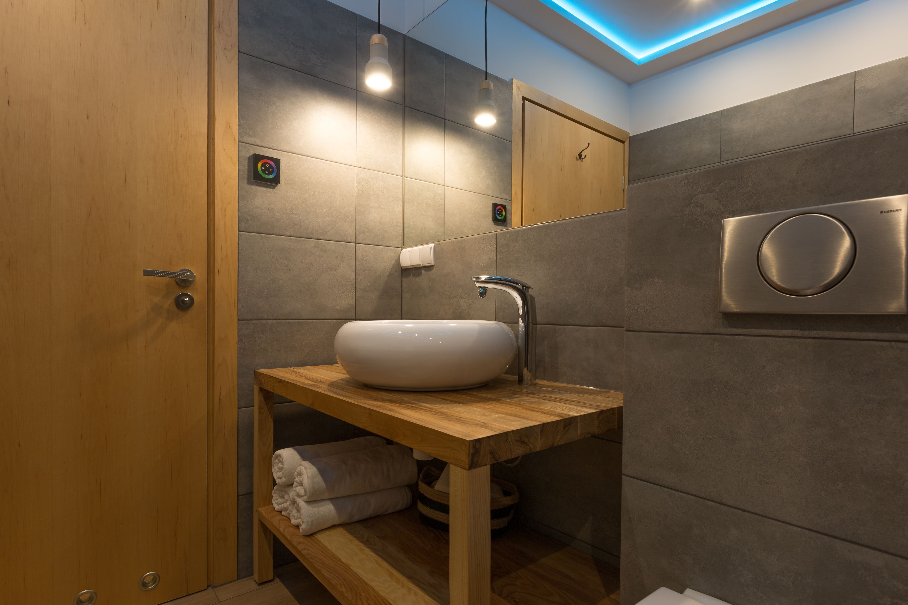Un baño moderno con tocador de madera, un lavamanos grande y ducha integrada.