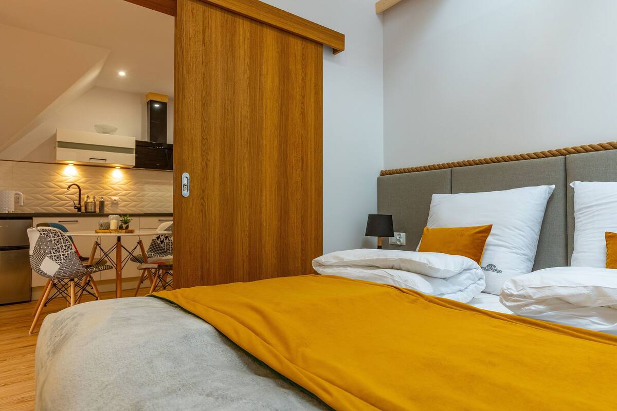 Une chambre d’hôtel avec un lit, une table de chevet, une lampe et une vue sur la cuisine.