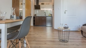 Une cuisine moderne avec des meubles en bois, un réfrigérateur en acier inoxydable et un coin repas comprenant une table et des chaises.