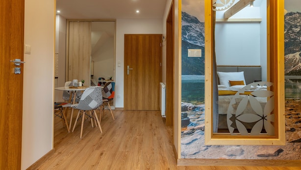Une chambre avec un lit, une table entourée de chaises et une vue sur une montagne et un lac, visible par la fenêtre.