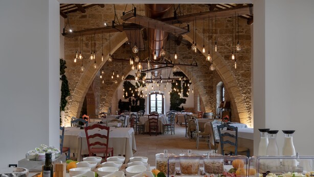 Montaje de un bufé de desayuno con diversas opciones de comida, y un interior rústico con paredes de piedra y luces colgantes.
