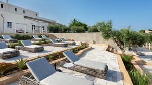 Un área de lounge en la azotea con sillones de sol y una pequeña mesa, rodeada de plantas y un edificio con la inscripción "Momentum".