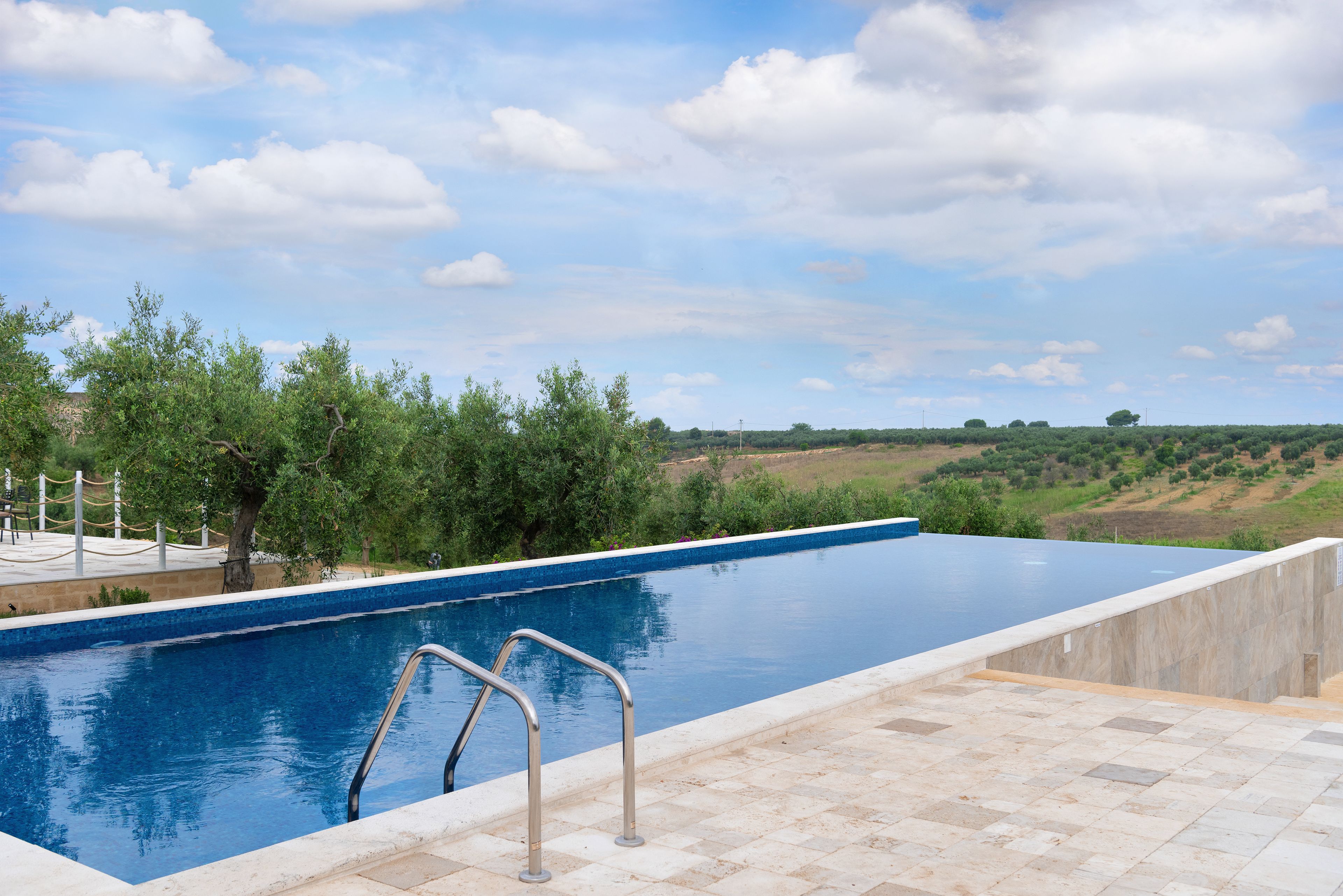 A rectangular swimming pool with a clear blue water surface, surrounded by a tiled deck area.