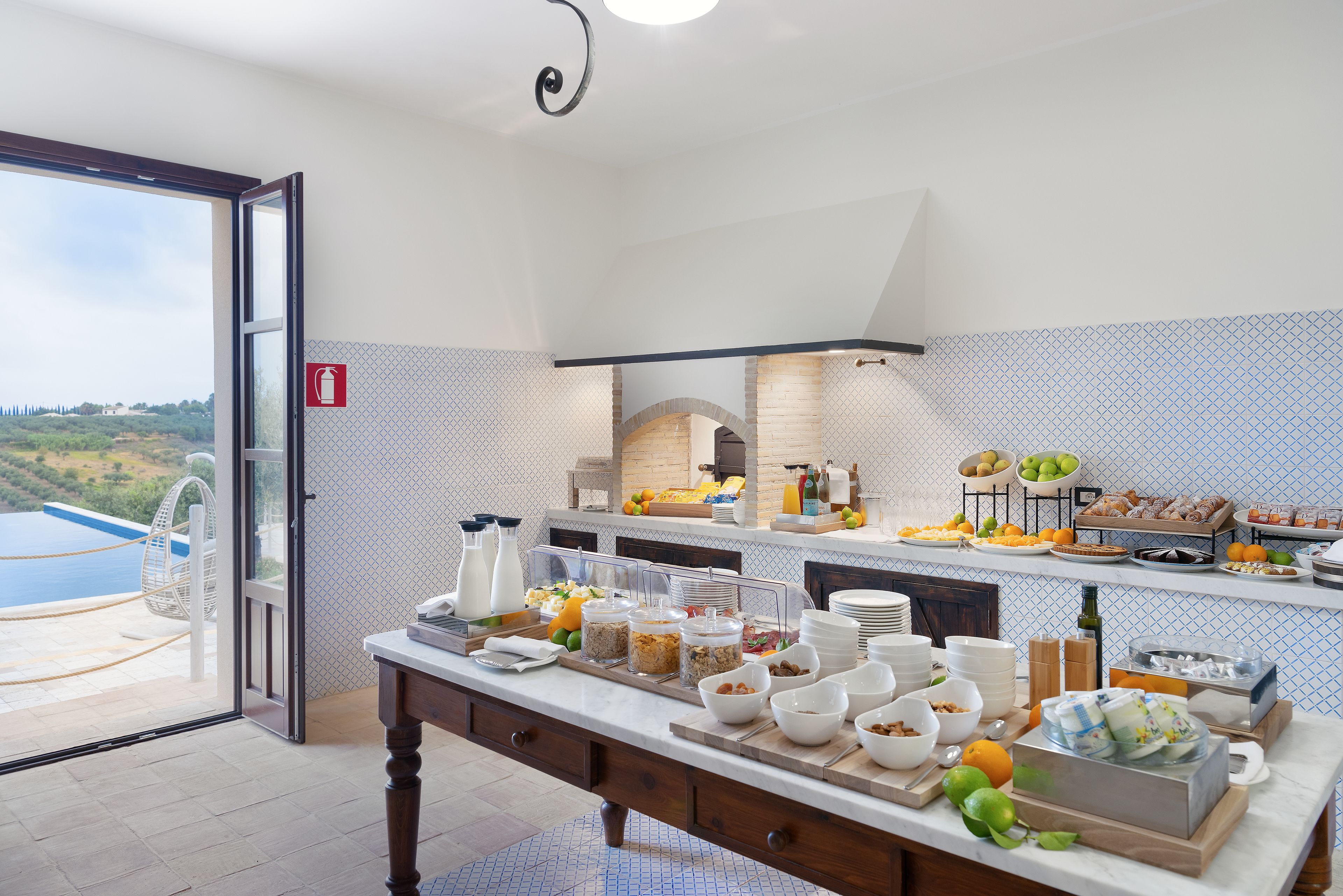 Un bufé de desayuno con diversas opciones de comida y vista a una piscina.