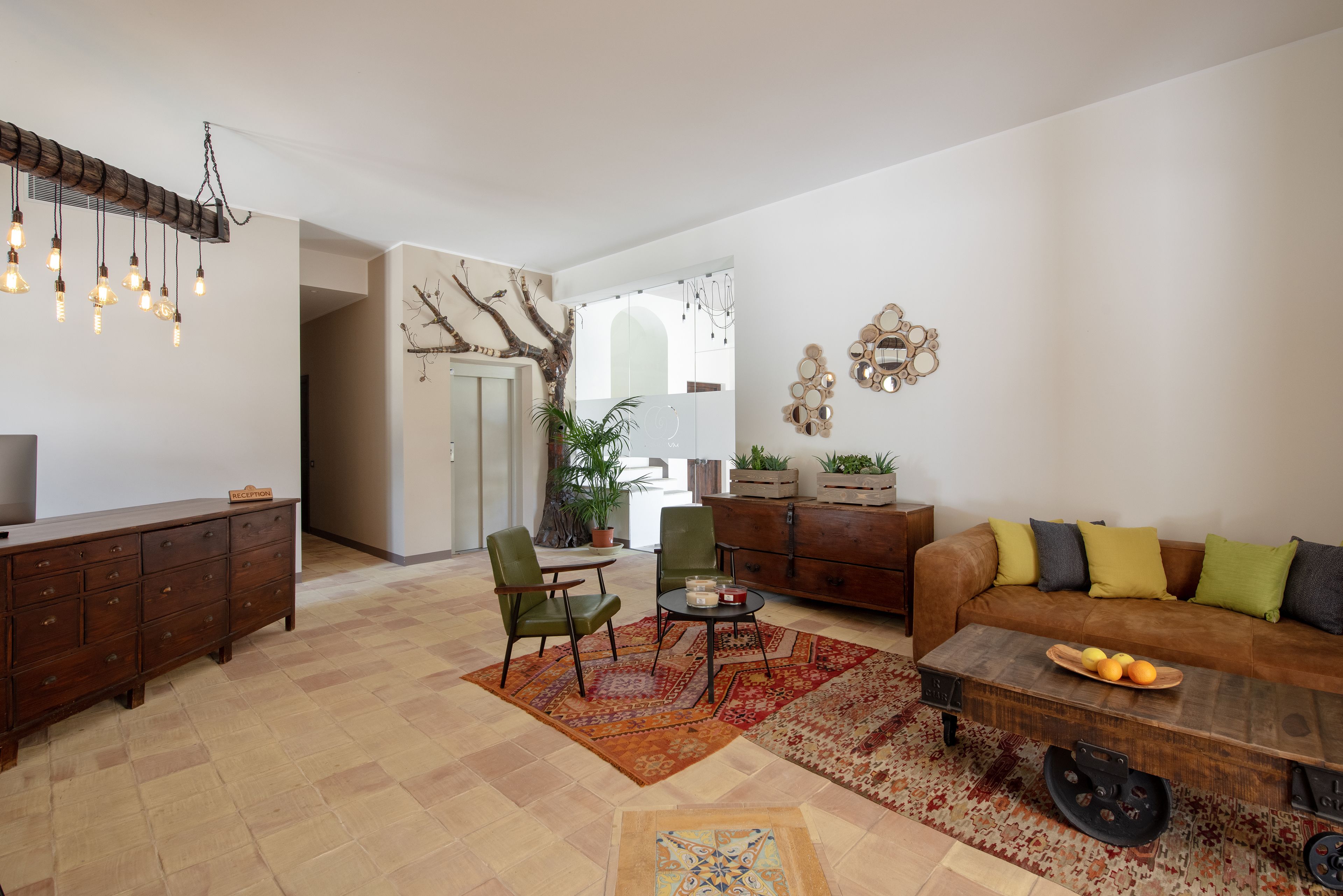 Una sala de estar con sofá, sillones, una mesa de centro, un aparador de madera y una araña.