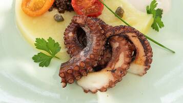 A plate with octopus, cherry tomatoes, capers, and parsley.
