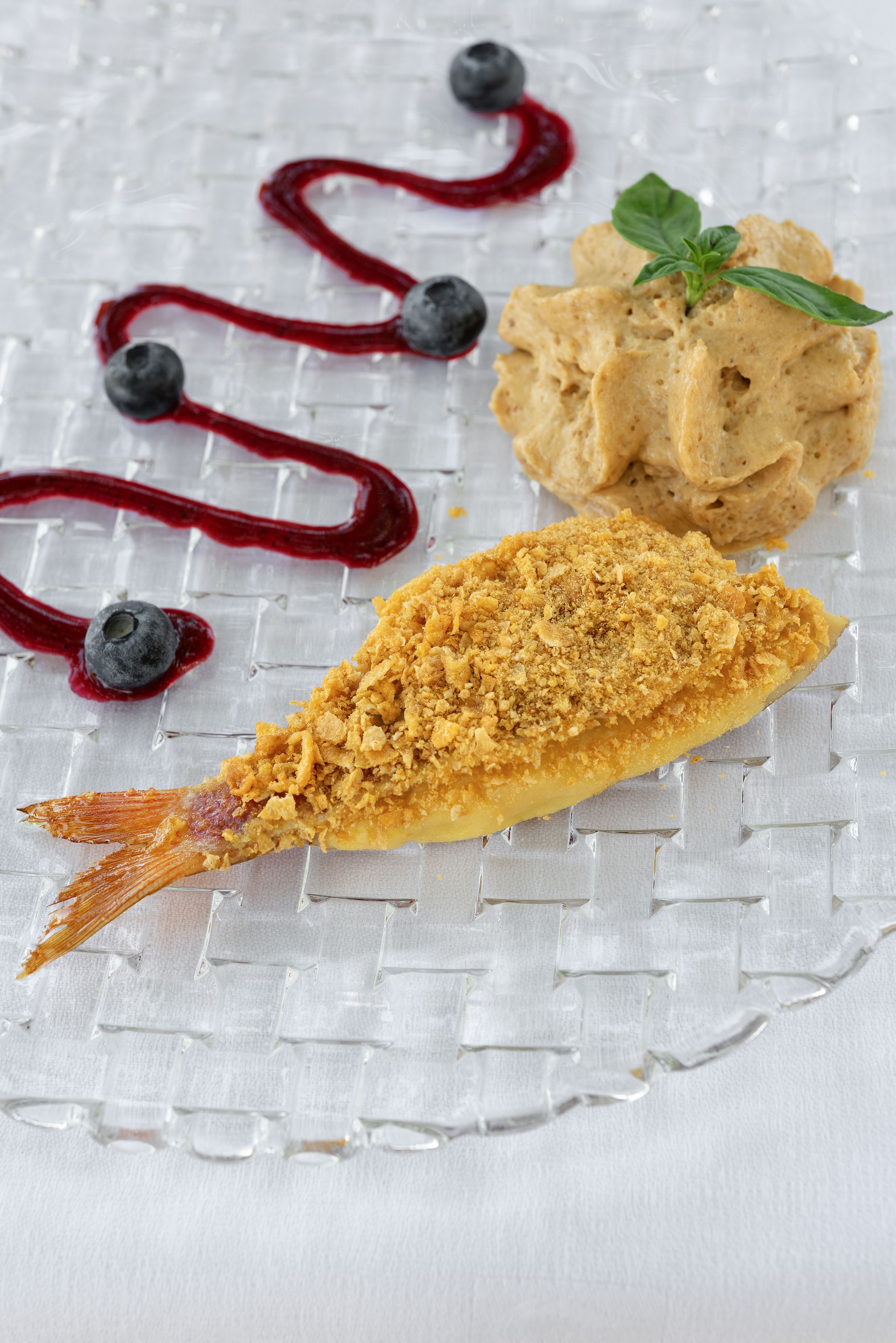 Ein Dessertteller mit frittiertem Fisch, zerbröselter Decke und Beerensoße.