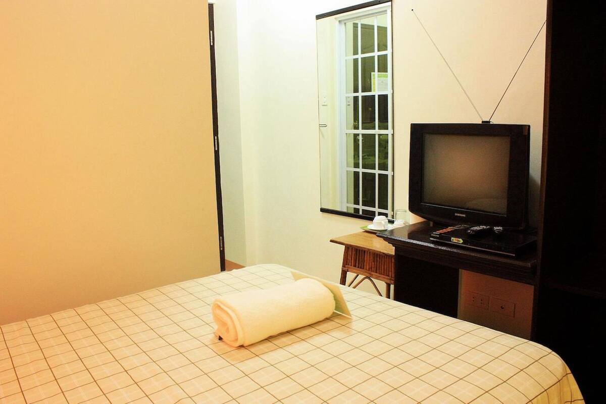 Une chambre d’hôtel avec un lit, une télévision, une fenêtre et une petite table.