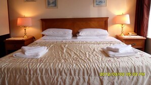 A hotel room with a large bed, two bedside tables with lamps, and four framed pictures on the wall. - Thorpe Lodge Hotel (Peterborough)