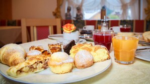 A breakfast table with pastries, a glass of orange juice, and a vase with a flower. - Pra Fiorì (Mazzin)