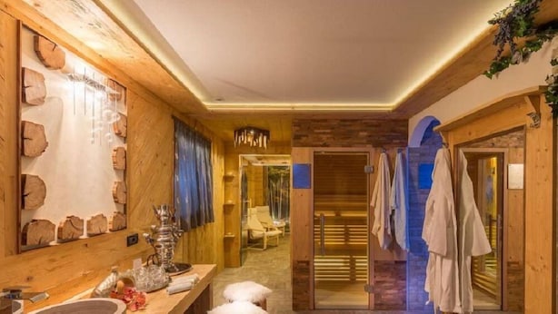 A wooden interior with a large mirror, a stone basin, and a sauna area. - Pra Fiorì (Mazzin)