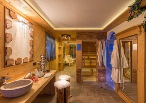 A wooden interior with a large mirror, a stone basin, and a sauna area. - Pra Fiorì (Mazzin)