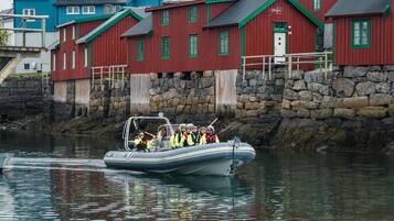 A boat with passengers, a stone wall, and red buildings with green trim.