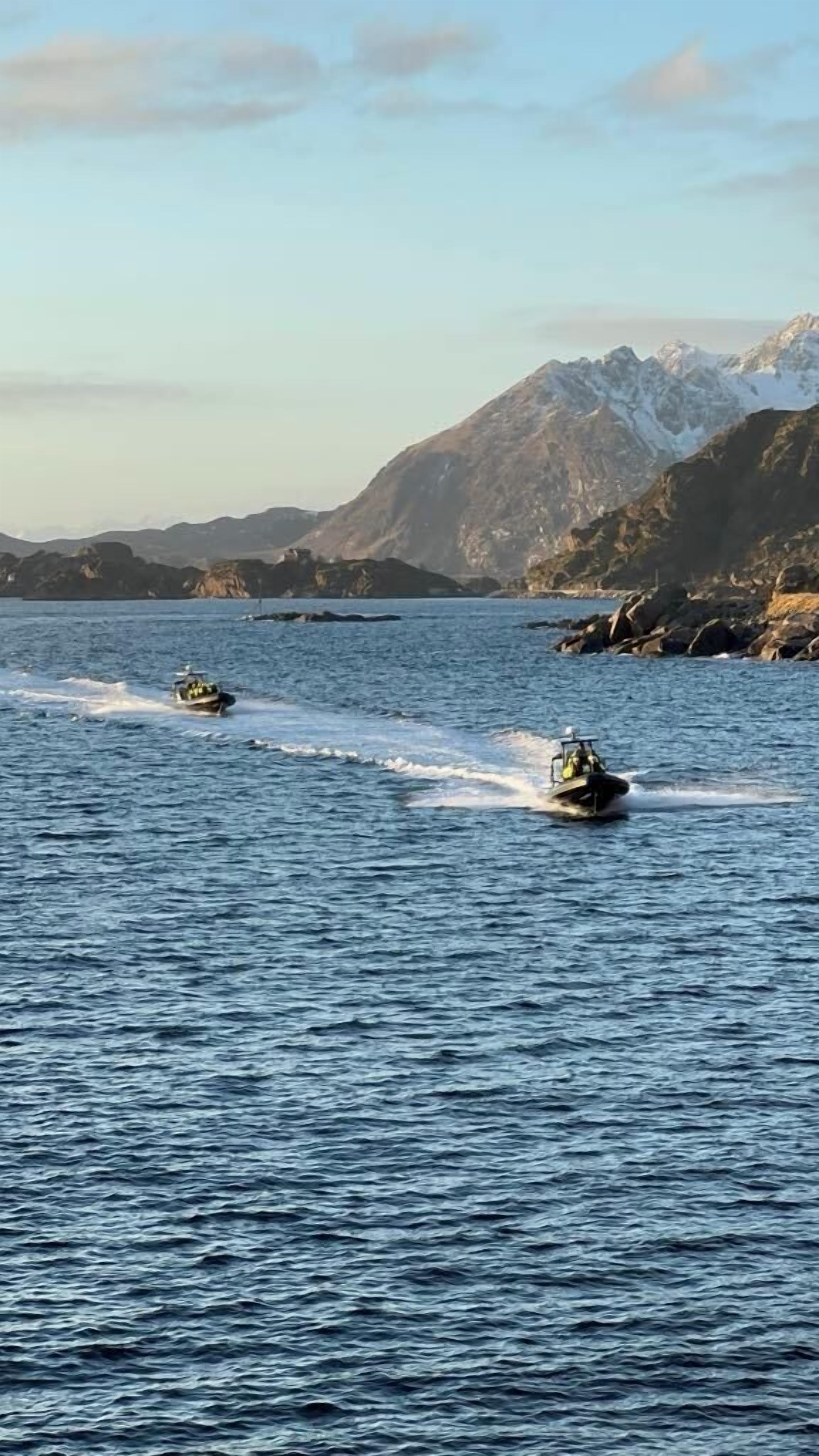 Two speedboats on a calm body of water with mountains in the background.