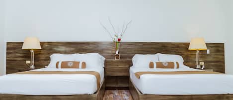 Una habitación de hotel con dos camas individuales, cabeceros de madera, ropa de cama blanca y lámparas de noche.