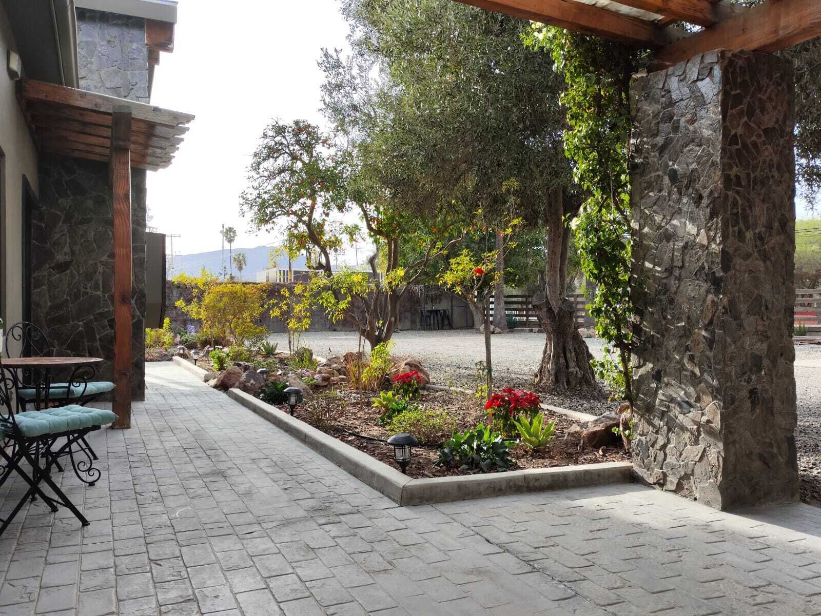 Ein Innenhof mit Steinmauern, einer gepflasterten Terrasse und Außenbestuhlung.