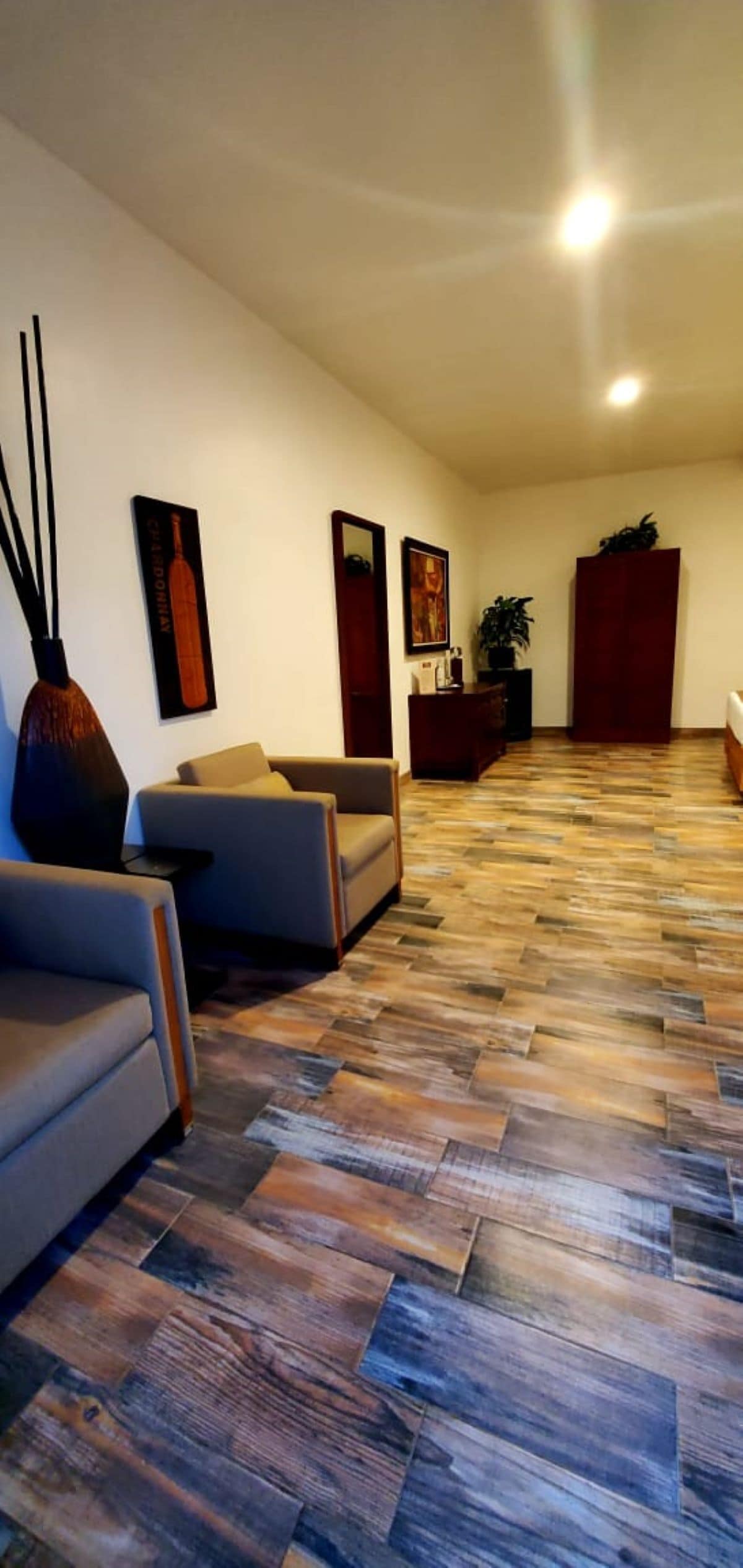 A modern living room with a herringbone wood floor, a sofa, a coffee table, and a decorative vase.