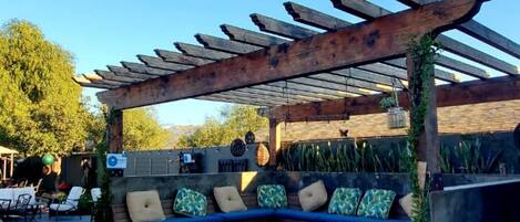 Un espace extérieur aménagé avec une pergola, des bancs en pierre et un chemin, le tout abrité.
