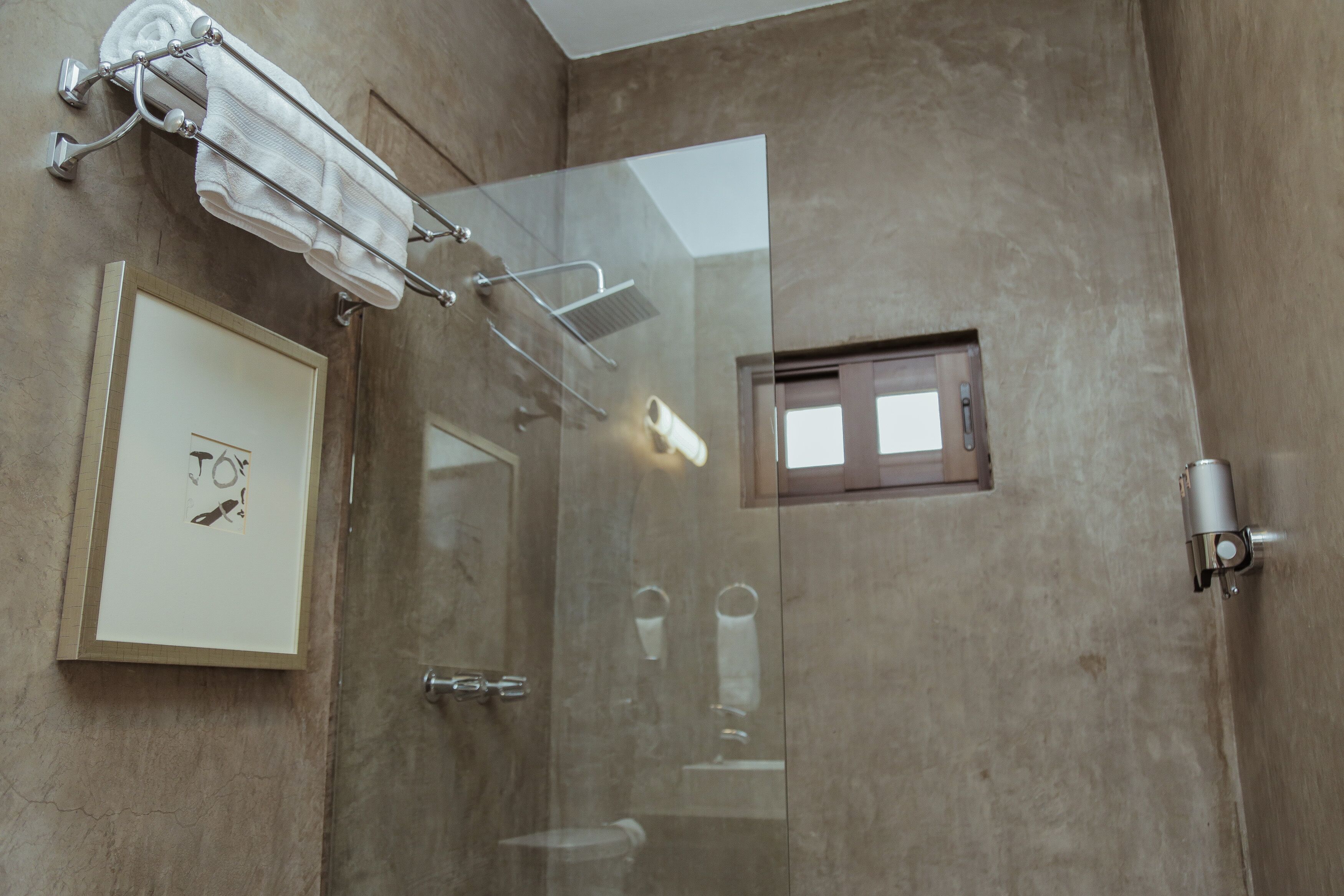 A modern bathroom with a glass shower enclosure, a towel rack, and a framed picture on the wall.