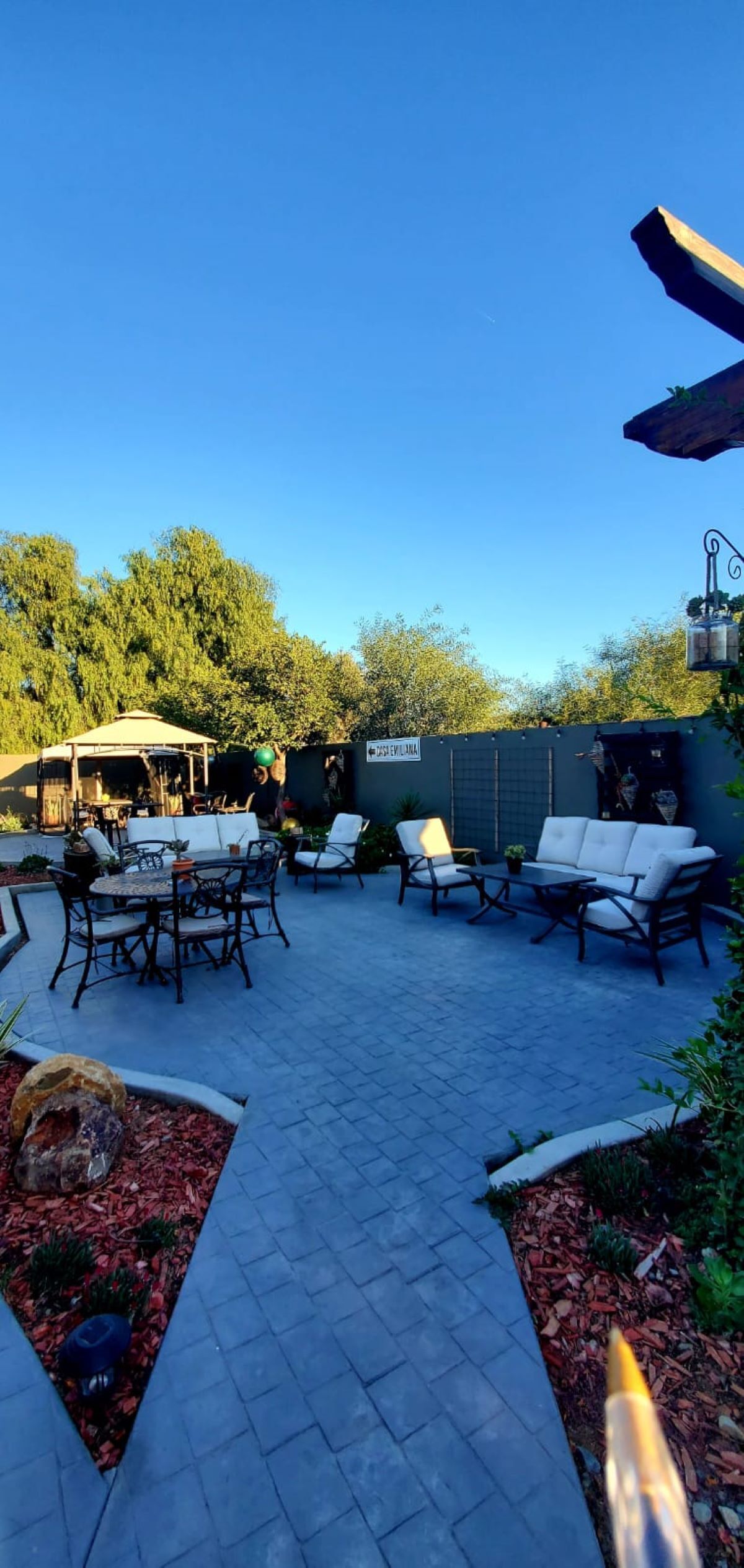 An outdoor patio area with seating arrangements, a pathway, and a wall with a sign.